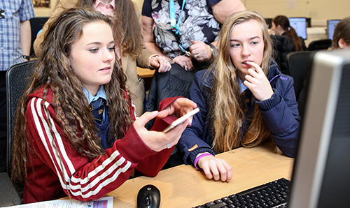 Schoolchildren working with their mobile phones and a computer