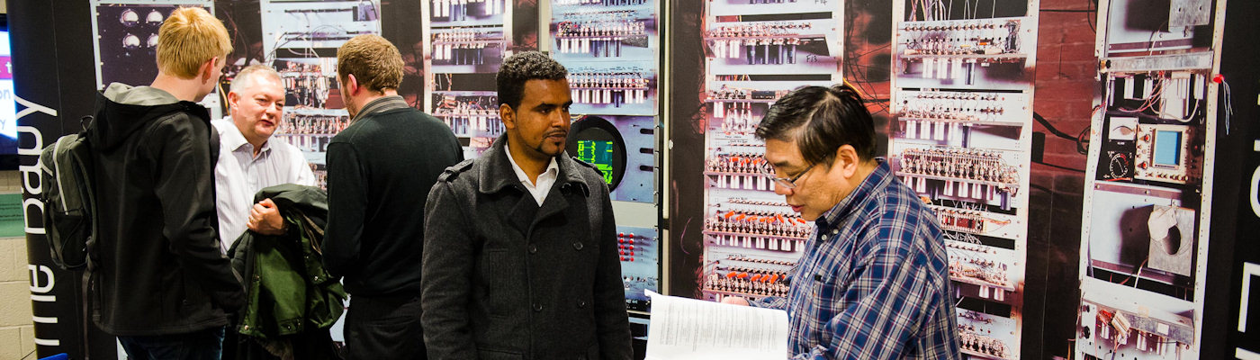 Older man talking to younger man in front of a display