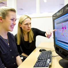 Caroline Jay pointing at computer screen and student smiling