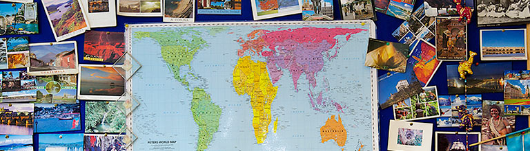 Pin board with map of the world and postcards pinned to it