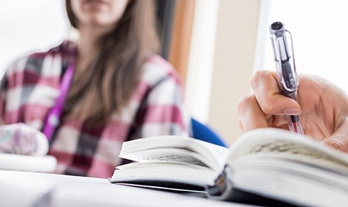 A hand holding a pen, writing notes