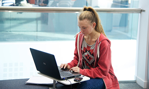 female student sat at a laptop